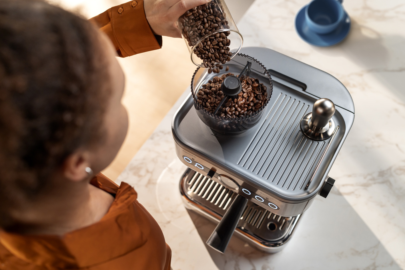 Jauna moteris pila kavos pupeles į „Philips Barista brew“ kavos pupelių talpyklą
